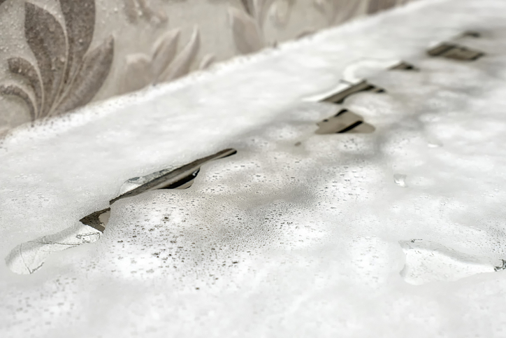 Close-up showing water and foam trapped above a clogged shower drain.