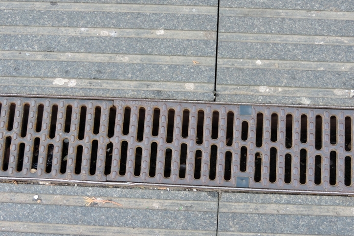Outdoor trench drain grate set in concrete pavement.